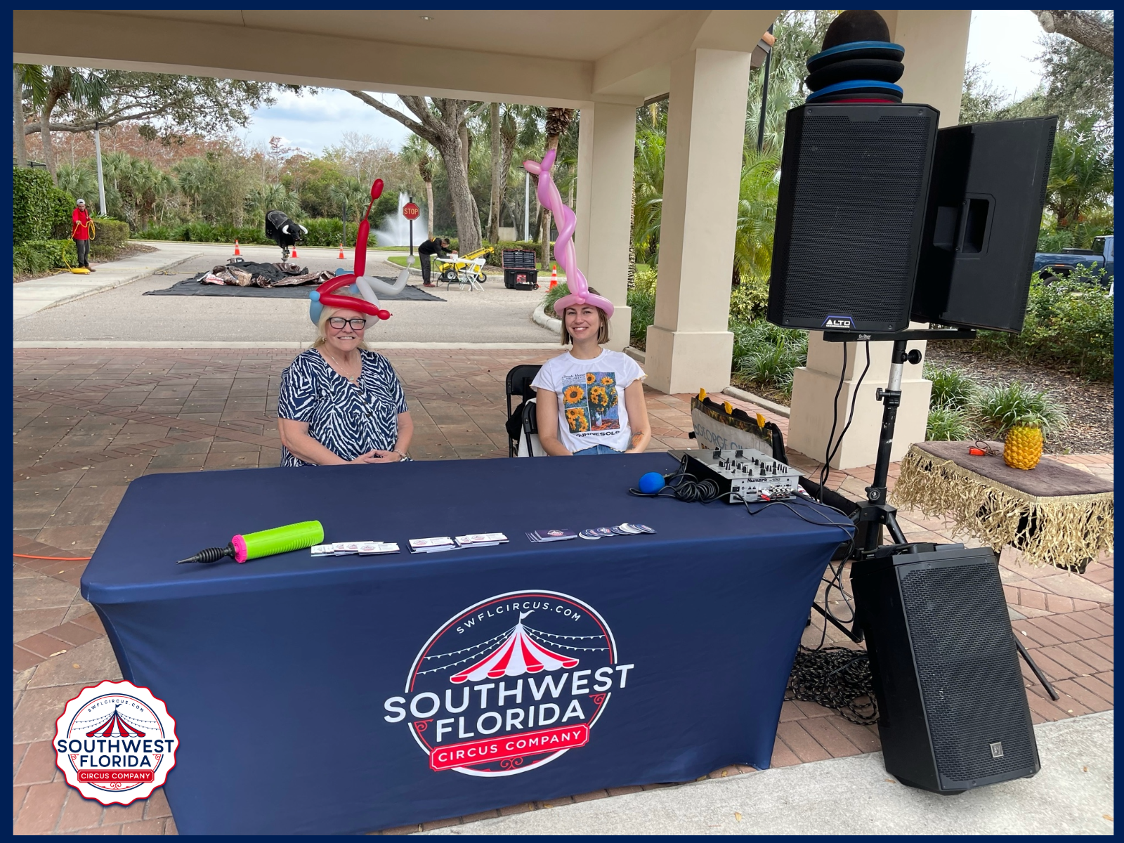 Festival Showtime Experience 5 Two Smiling Guests Wearing Balloon Hats Beside The Southwest Florida Circus Company Outdoor Entertainment Setup.